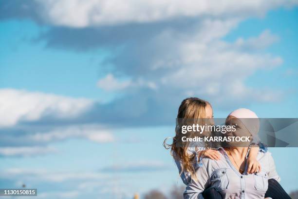 a woman with cancer is next to her daughter. a girl is hugging a woman happy - cancer prevention stock pictures, royalty-free photos & images