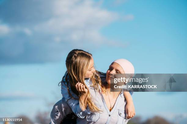 a woman with cancer is next to her daughter. a girl is hugging a woman happy - happy patient fotografías e imágenes de stock