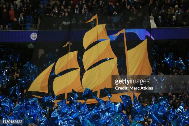 Banner featuring the ship from the Manchester City club crest is held by fans prior to the UEFA Champions League Round of 16 Second Leg match between...