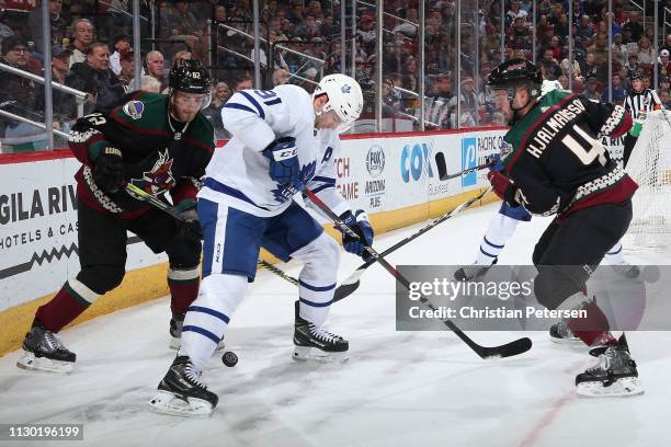 John Tavares of the Toronto Maple Leafs attempts to control the puck against Niklas Hjalmarsson and Jordan Oesterle of the Arizona Coyotes during the...