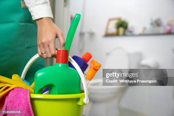 the cleaning woman is standing in the bathroom holding a blue bucket full of chemicals and facilities for storing her hands. - cleaning product stock pictures, royalty-free photos & images