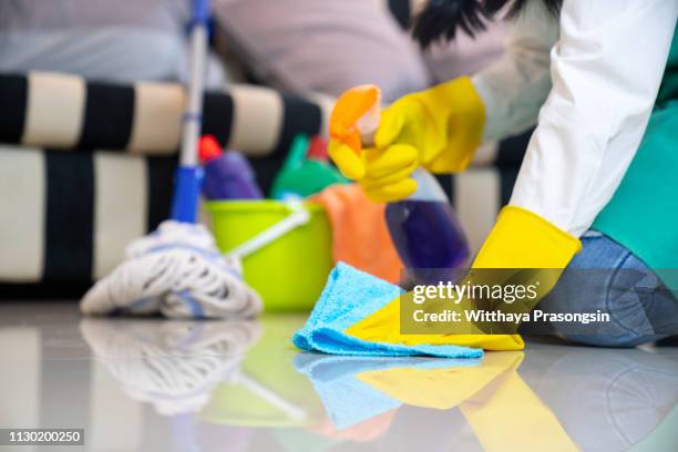 husband housekeeping and cleaning concept, happy young  woman in blue rubber gloves wiping dust using a spray and a duster while cleaning on floor at home - kitchen mop stock pictures, royalty-free photos & images