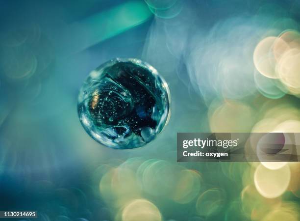 artistic composition of blue glass ball on glittered background - mundo de cristal fotografías e imágenes de stock