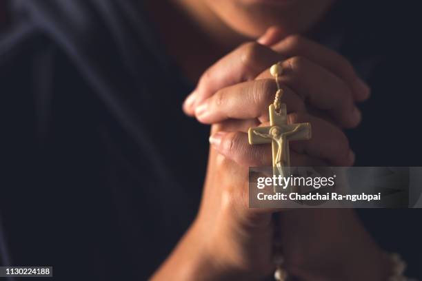 christian woman praying in church. hands crossed and holy bible on wooden desk. background - croci foto e immagini stock