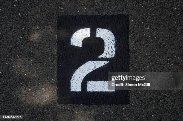 parking spot number 2 stencilled in paint on an asphalt parking lot - second stock-fotos und bilder