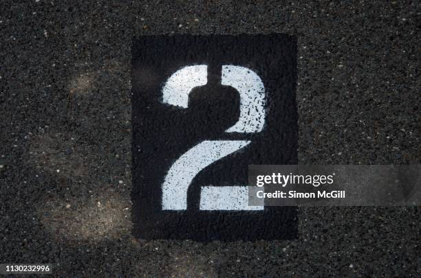 parking spot number 2 stencilled in paint on an asphalt parking lot - number 2 stock pictures, royalty-free photos & images