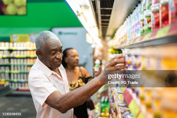 afro senior couple at choosing products at the supermarket - older black people shopping stock pictures, royalty-free photos & images