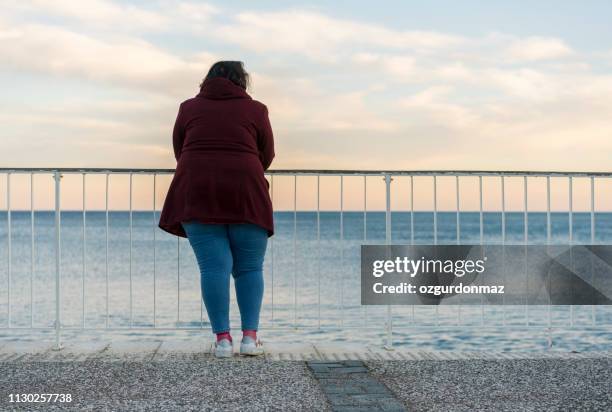 giovane donna grassa in piedi da sola sulla spiaggia - chubby foto e immagini stock