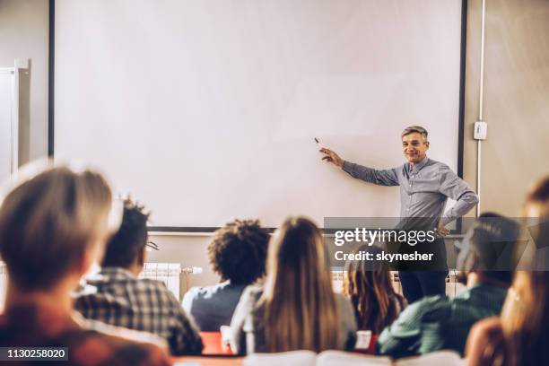 happy professor teaching a lecture on visual screen in the classroom. - projection equipment stock pictures, royalty-free photos & images
