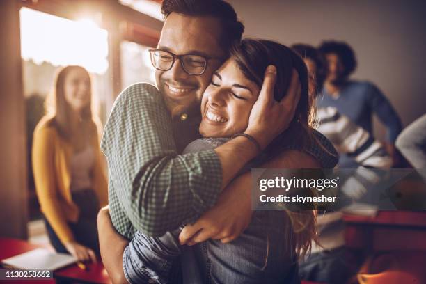 pareja feliz colegio abrazados en el aula. - abrazo fotografías e imágenes de stock