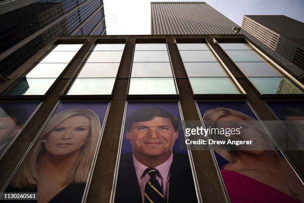 Advertisements featuring Fox News personalities, including Tucker Carlson , adorn the front of the News Corporation building, March 13, 2019 in New...