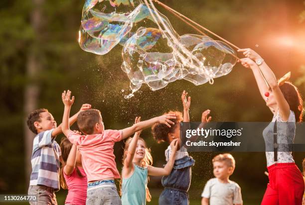 spelen met regenboog bubbels in het park! - bellenblaas stockfoto's en -beelden