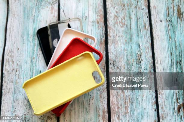 set of colored silicone covers for smart phone on rustic wooden table - coprire foto e immagini stock