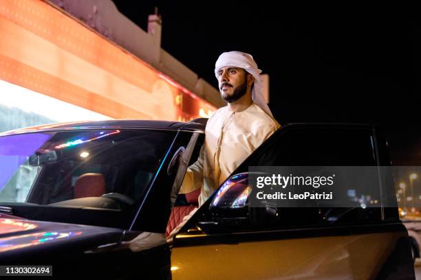 arab man out of a dubai parking lot hanging out at night - arab car stock pictures, royalty-free photos & images