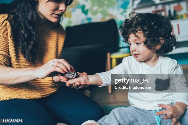 moeder geven een geneeskunde aan kind - homeopathie stockfoto's en -beelden