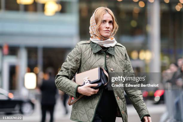 Blanca Miro wears a Burberry scarf over the head, a green puffer jacket, a Burberry bag, black pants, outside Burberry, during London Fashion Week...