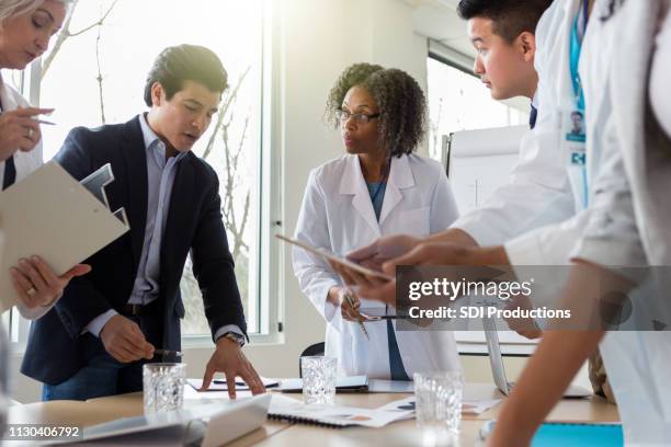 male hospital administrator talks with group of doctors - medical sales representative stock pictures, royalty-free photos & images