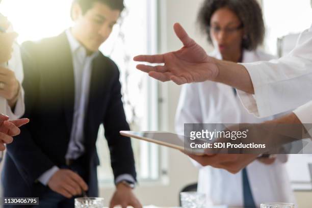 close up of doctor's hand gesturing and holding a digital tablet - medical sales representative stock pictures, royalty-free photos & images