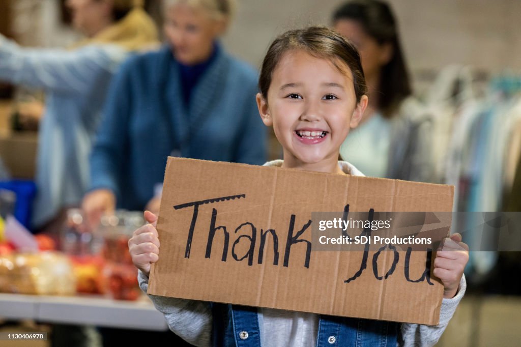 Banco de alimentos jovem adorável voluntário mantém sinal 'Obrigado'