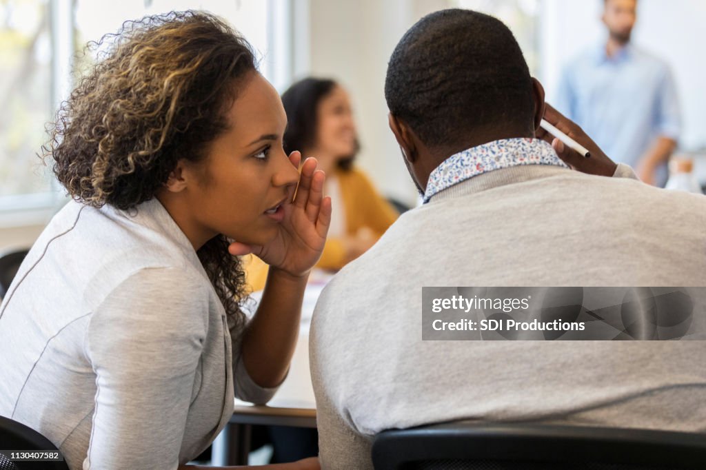 Entreprise femme chuchote dans l’oreille de collègue