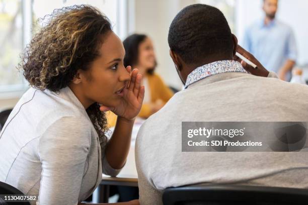 business woman whispers in colleague's ear - secrets stock pictures, royalty-free photos & images