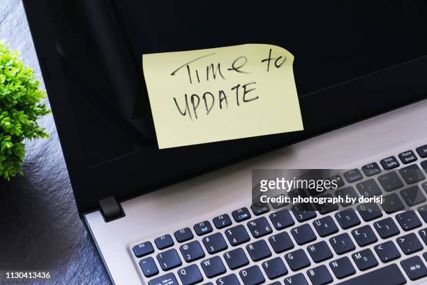 laptop and yellow paper on screen with text written 'time to update' - concept updates stock pictures, royalty-free photos & images