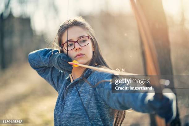 teenage girl shooting a bow - bow hunting stock pictures, royalty-free photos & images