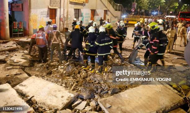 Rescue workers and fire brigade personnel remove debris at the site of a footbridge after its collapse, outside the Chhatrapati Shivaji Maharaj...