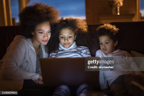 afro-americana mãe e os filhos dela assistindo desenhos no laptop em casa. - daughters of darkness - fotografias e filmes do acervo