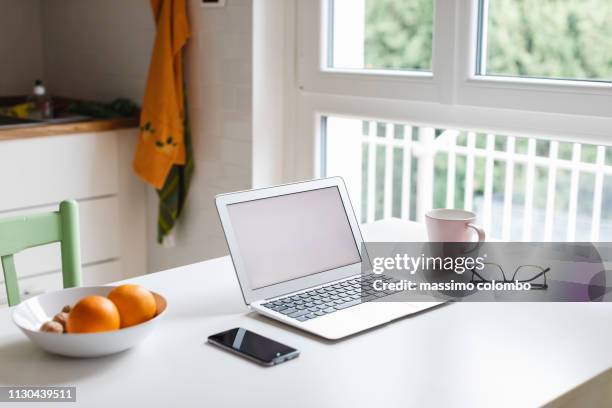 laptop and smartphone on the kitchen table - laptop kitchen table stock pictures, royalty-free photos & images