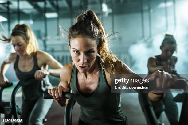 femme athlétique déterminée au cours de l’exercice classe en vélo dans un gymnase. - cours de spinning photos et images de collection