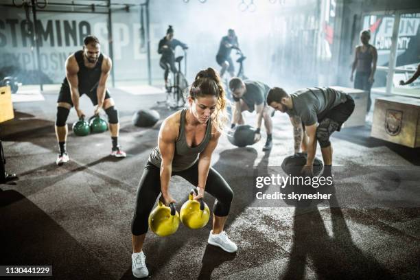 gran grupo de atletas ejerciendo fuerza de cross entrenamiento en un gimnasio. - crossfit fotografías e imágenes de stock