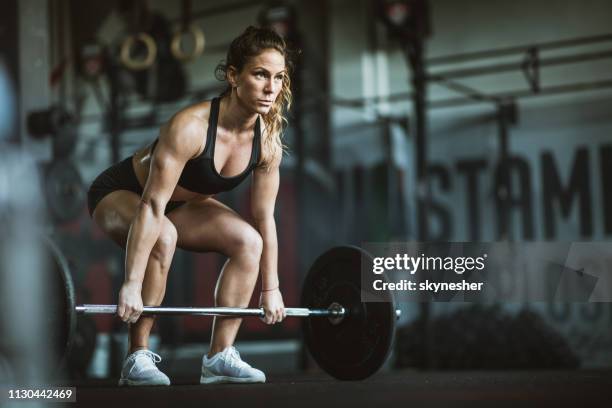 concentrated athletic woman exercising deadlift in a gym. - snatch weightlifting stock pictures, royalty-free photos & images