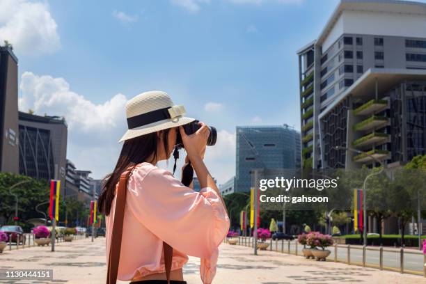 joven mujer asiática de turismo en putrajaya malasia, sosteniendo una cámara de cine dslr, relajante y ejoying tomar fotos de viaje - estado de selangor fotografías e imágenes de stock