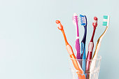 Multi-colored toothbrushes in a glass cup, blue background