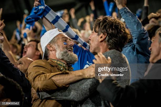 grupo de espectadores que animan en estadio - futbol fotografías e imágenes de stock