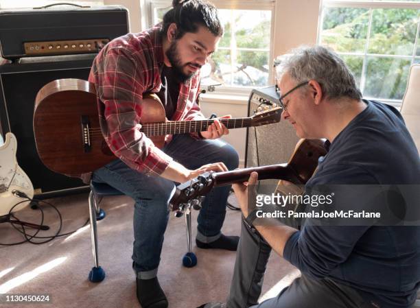 hispanic young man teaching mature caucasian man to play guitar - acoustic guitarist stock pictures, royalty-free photos & images