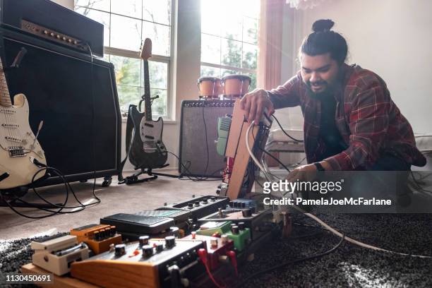 uomo ispanico che collega i cavi per i pedali degli effetti chitarra - bongo foto e immagini stock