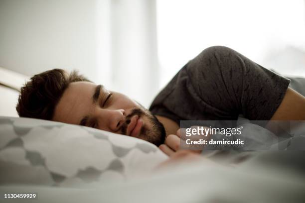 young man sleeping in bed at home - dreamlike stock pictures, royalty-free photos & images
