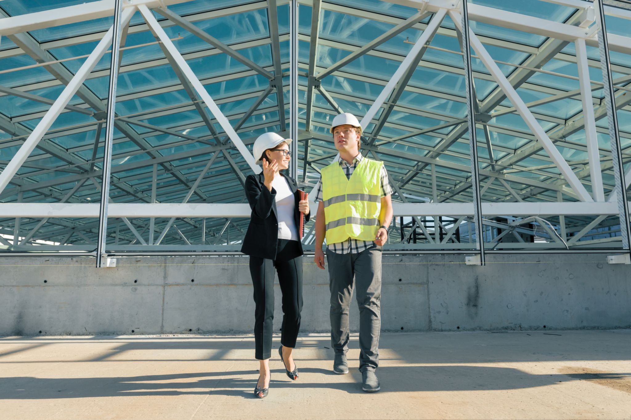 Woman engineer and man builder at construction site. Building, development, teamwork and people concept Woman engineer and man builder at construction site. Building, development, teamwork and people concept