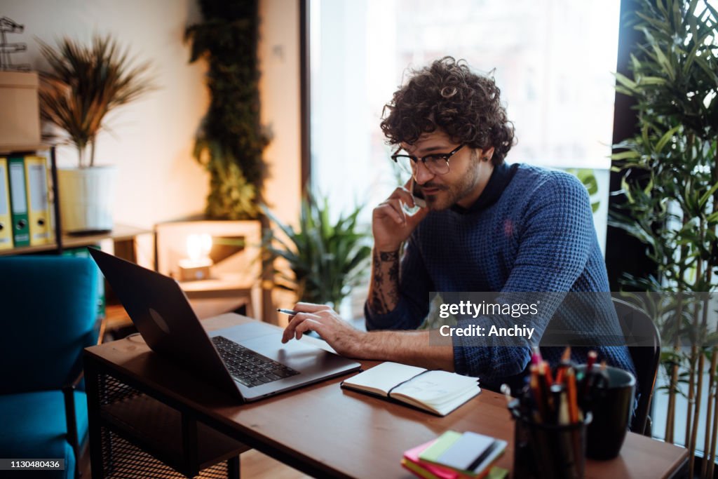 Young man talking on the phone in his home office