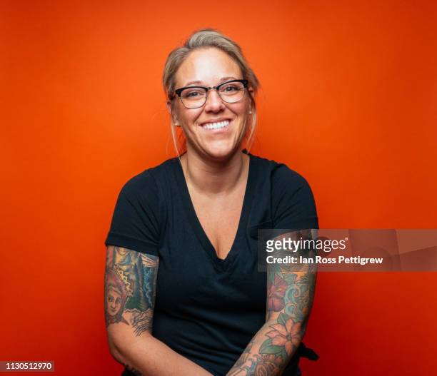 smiling blond woman with tattoos on orange background - tatouage femme photos et images de collection