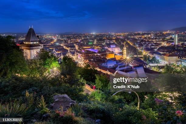 beautiful view of clock tower, landmark, on high mountain after sunset time in center of graz city, austria, europe - graz stock-fotos und bilder