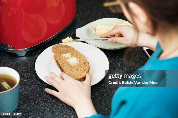 woman puts butter on toast in kitchen. - untar de mantequilla fotografías e imágenes de stock