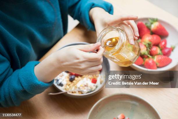 woman takes honey from jar with spoon for breakfast. - honey stock pictures, royalty-free photos & images