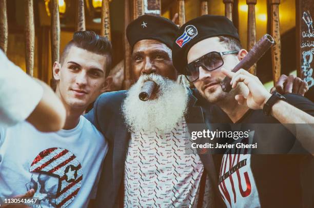 retrato de hombre cubano y turistas fumando puros - fumando stockfoto's en -beelden