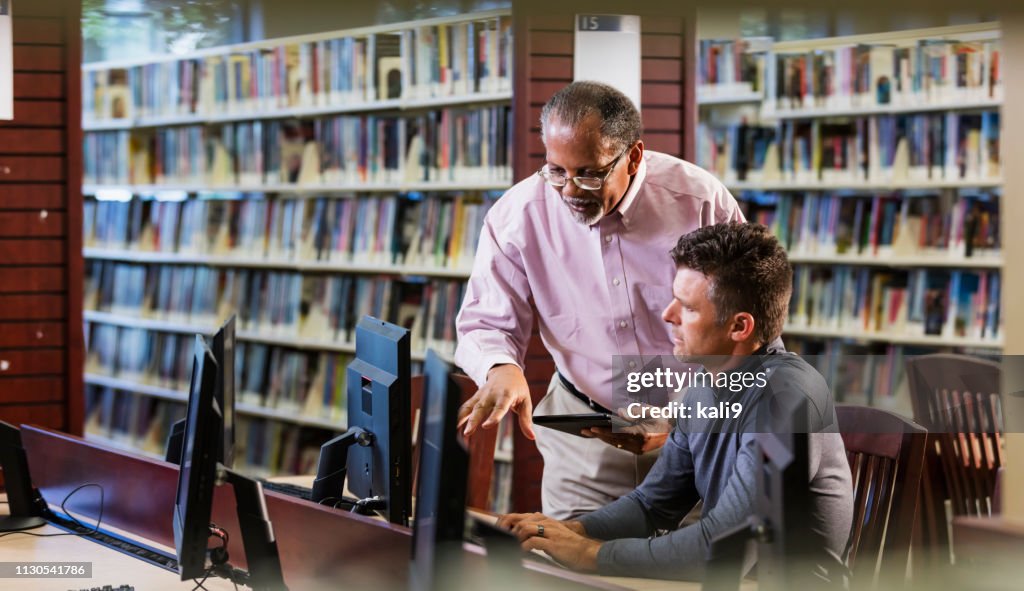 Two men in library looking at computer screen