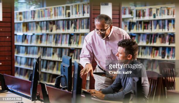 two men in library looking at computer screen - librarian stock pictures, royalty-free photos & images