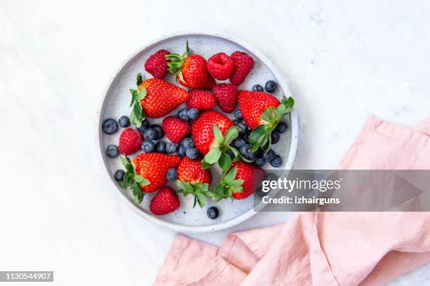 mixed berries in conrete plate on marble background with empty plate and copy space - berry fruit stock pictures, royalty-free photos & images