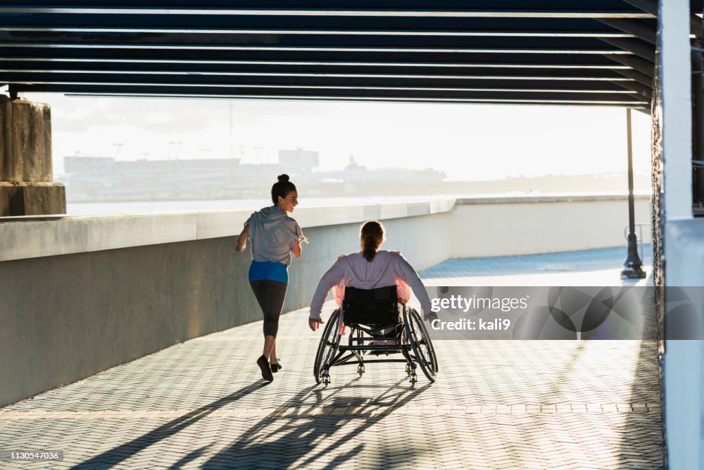 Junge Frau mit Spina bifida, hispanischer Freund joggen